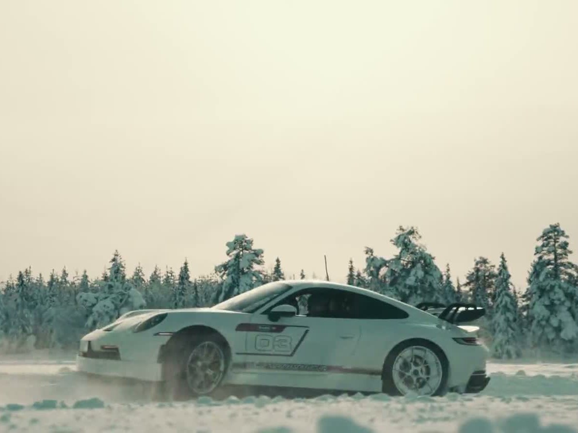 Porsche боком на льду, за ним заснеженный лес