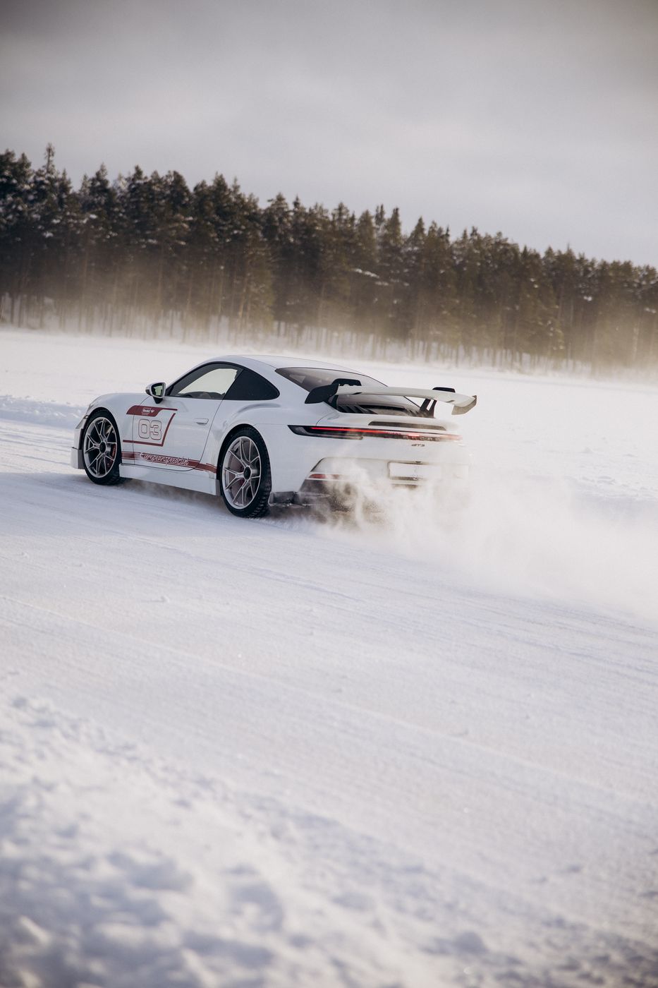 Porsche боком, за ним снежная пыль